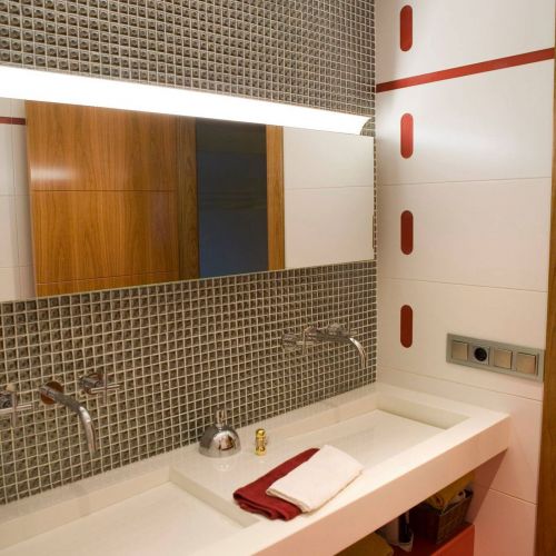 Baño con lavabos grandes rectangulares de color blanco y pared con detalles en color rojo