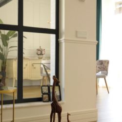 Interior de vivienda con decoración en primer plano y puerta con cortinas azules al fondo